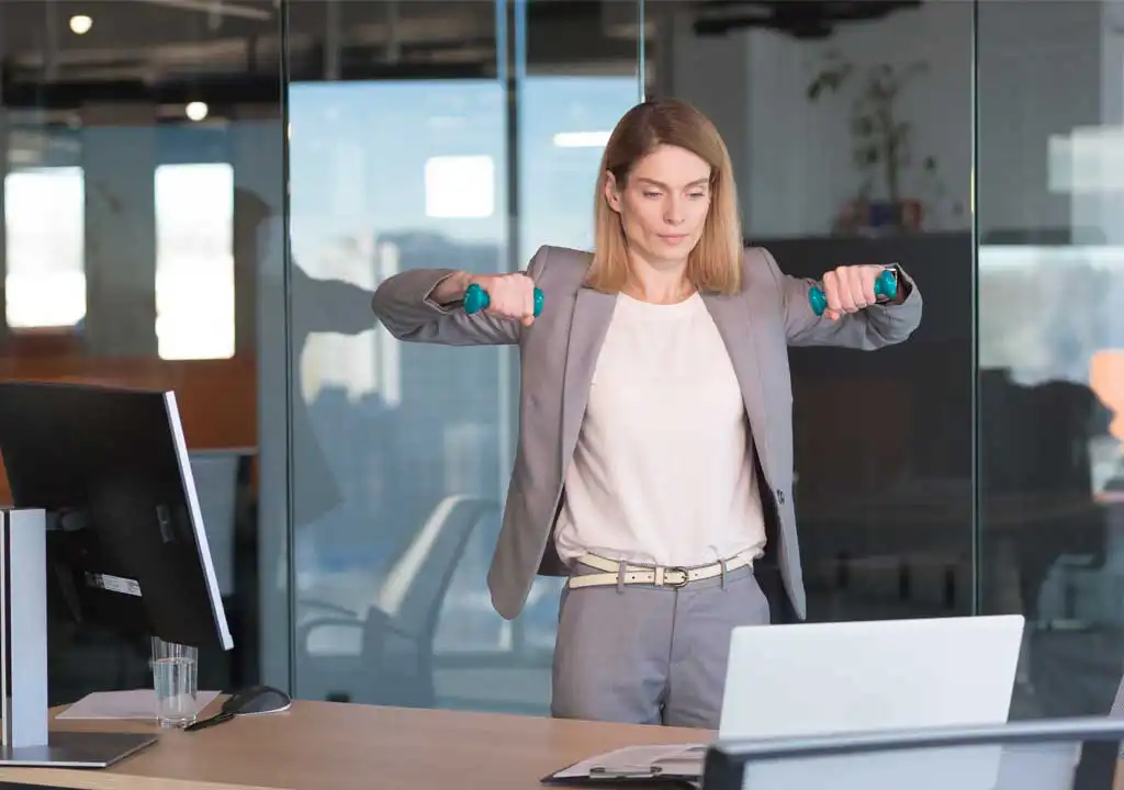 Devojka u kancelariji radi vežbe sa tegićima