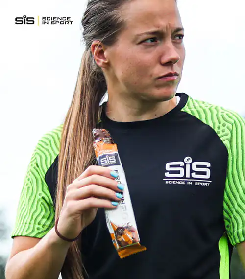 Devojka jede SiS sportsku proteinsku čokoladicu